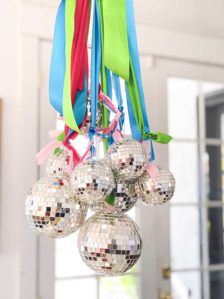 new year's eve party ideas disco ball decorations hanging from chandelier with ribbon