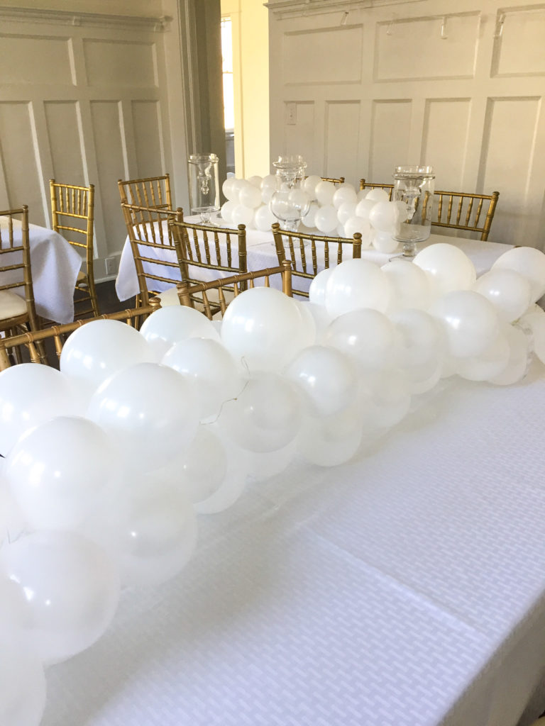 supper club table with white balloon garland centerpiece