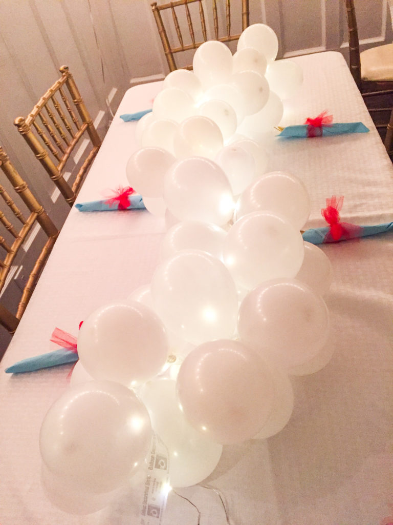 supper club table setting with white balloon garland and lights