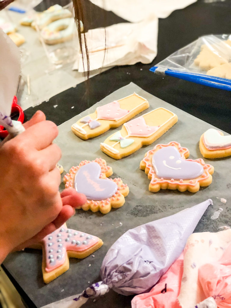 cookie artist using piping bag to decorate valentine cookies
