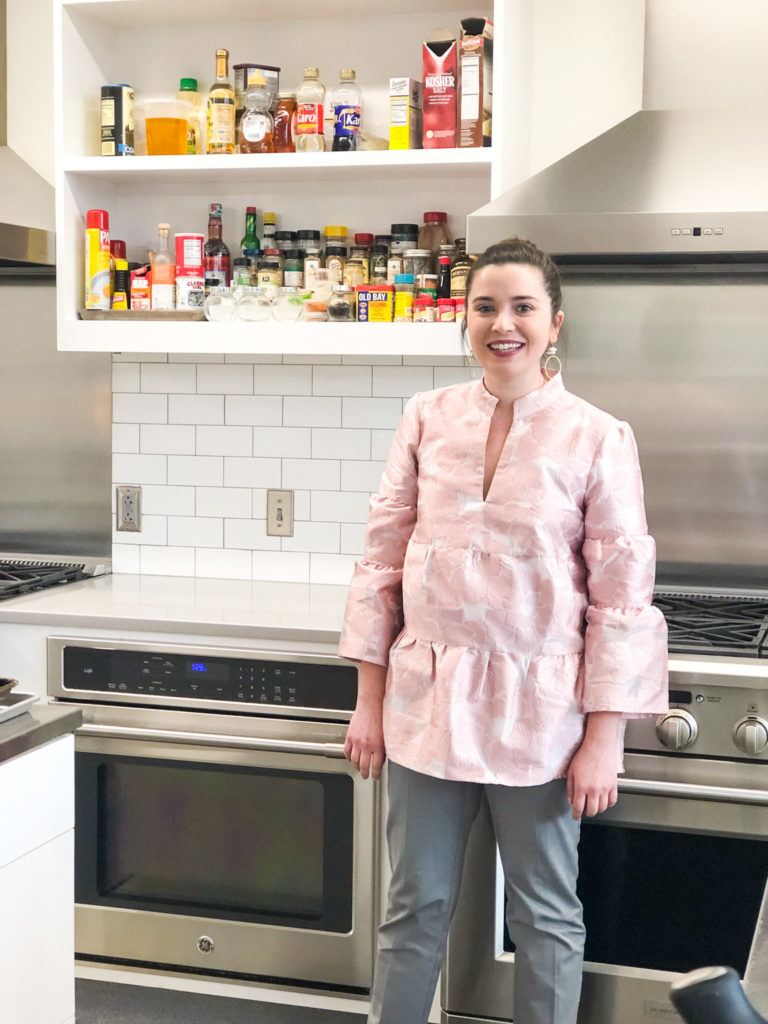 lady in kitchen wearing pink tiered shirt and gray pants