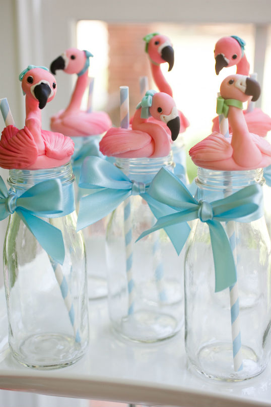 glass drink bottles with fondant flamingos on top tied with blue bow