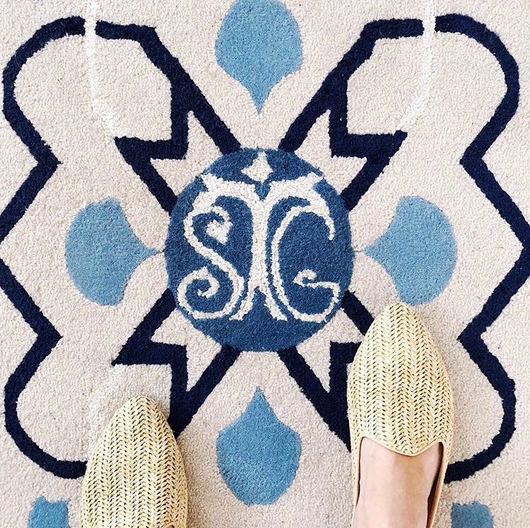 ivory rug with navy blue and light blue designs and monogram in middle