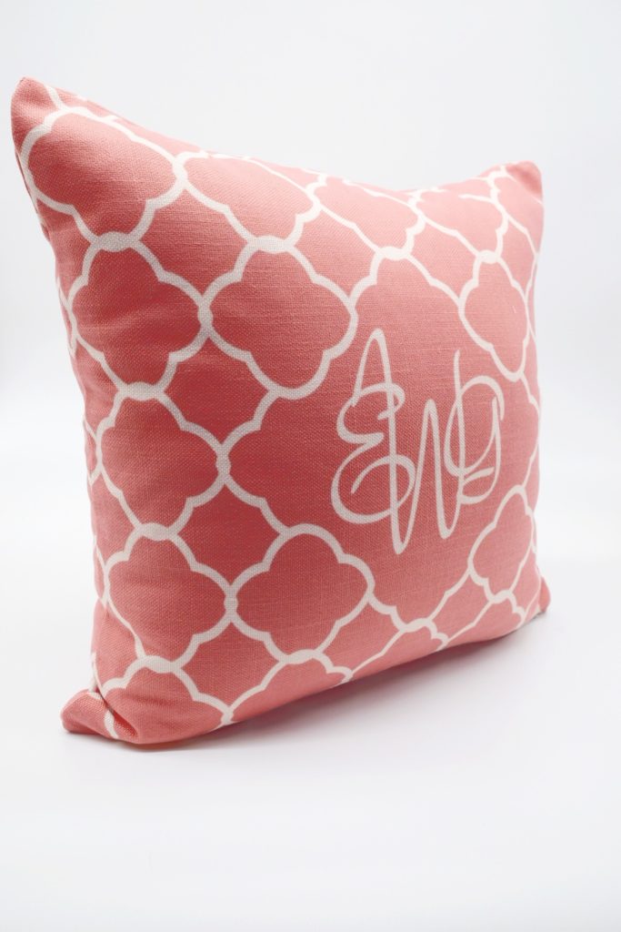 coral colored pillow with quatrafoil pattern in white with monogram in middle