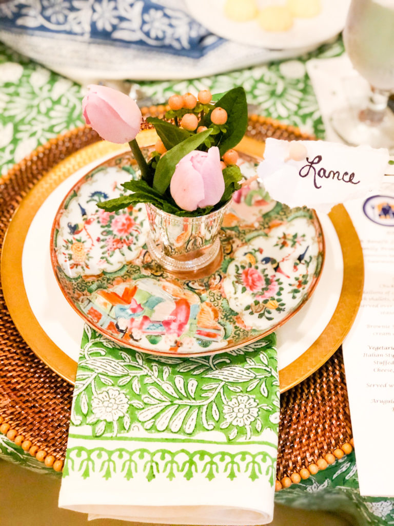 table setting with rose medallion china on gold plate with green napkin