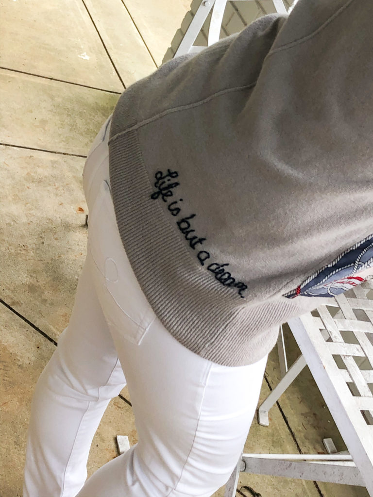 white jeans and back of sweater that reads life is but a dream
