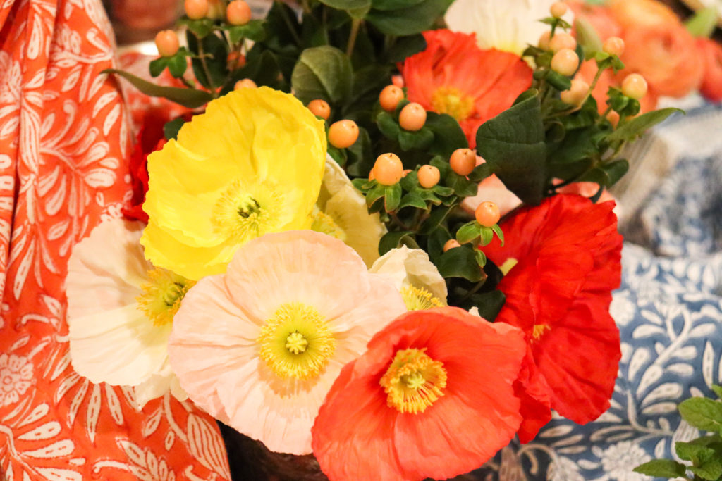 red pink yellow poppies in vase on table