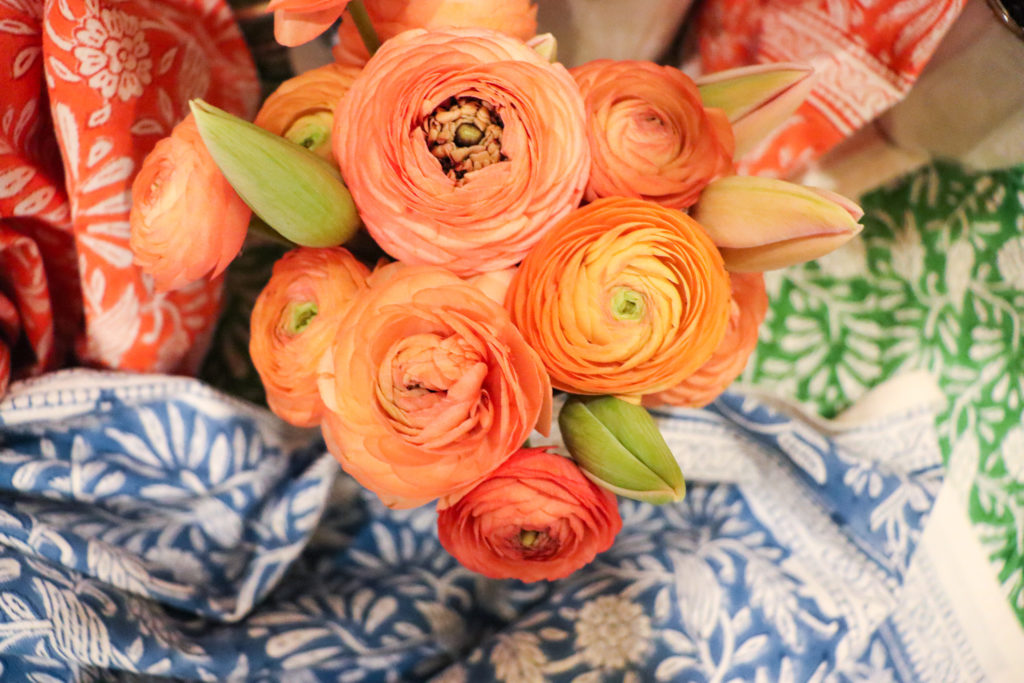 roses and ranunculus in orange and peach on. blue and green tablecloth