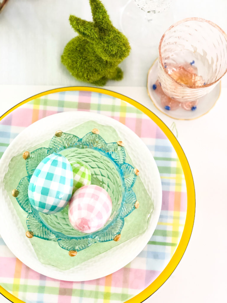 yellow charger plate with pastel plaid dinner plate on top with white salad plate on top with green glass bread plate on top with blue glass bowl filled with gingham pastel eggs