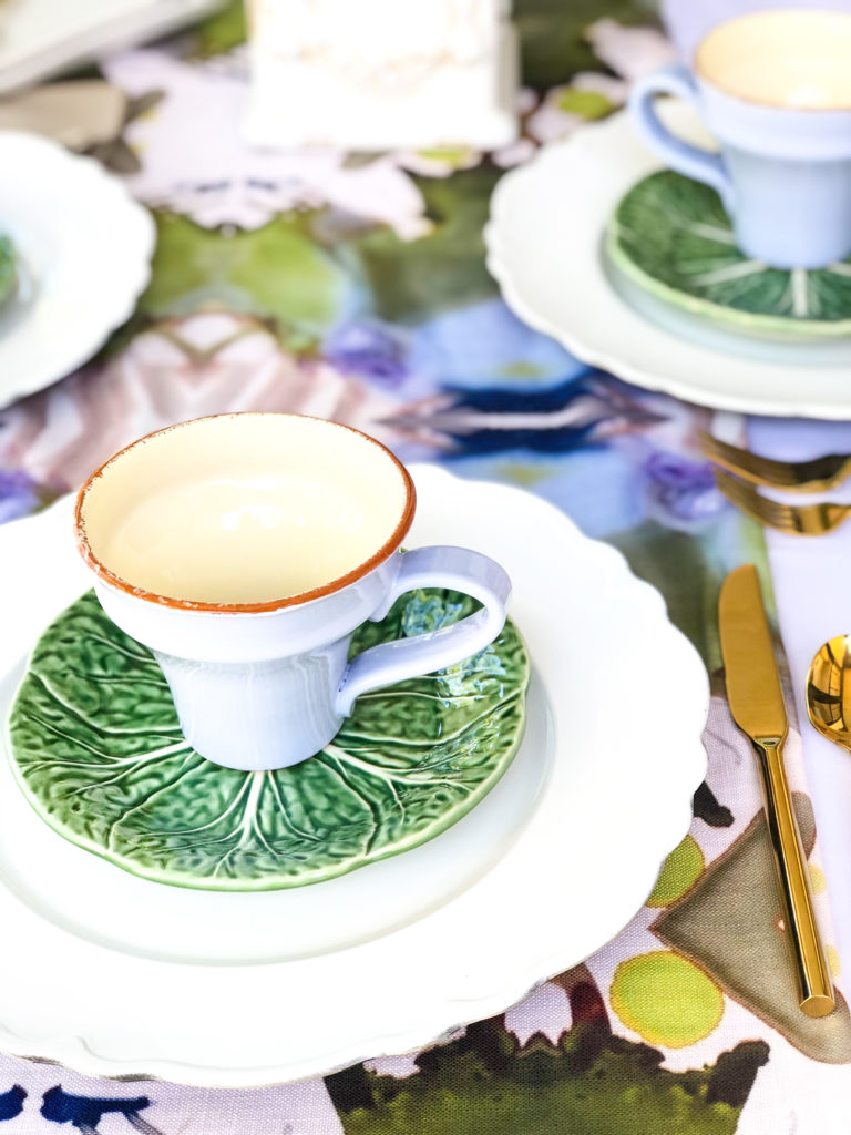 table set with artistic painted runner white plates green leaf salad plate lavender mug and gold flatware