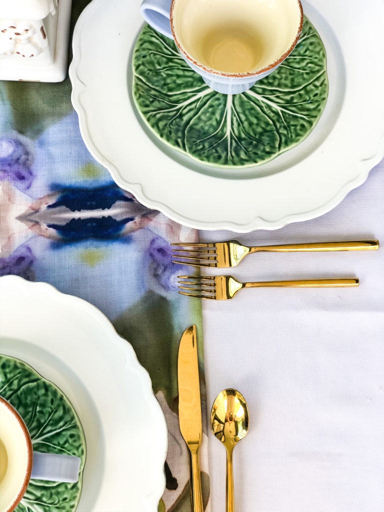 table set with windy oconnor art table runner with white plates green lettuce salad plates with mug and gold flatware