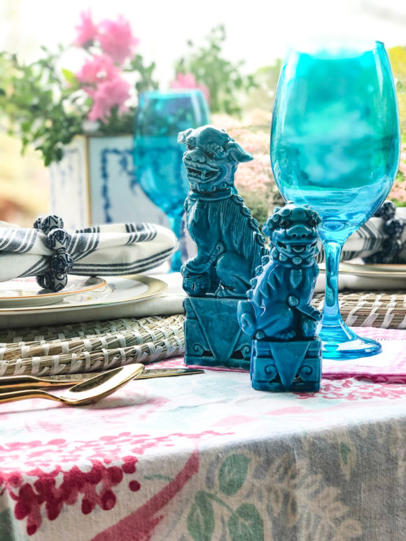 outdoor table set with plates and decorated with turquoise foo dogs