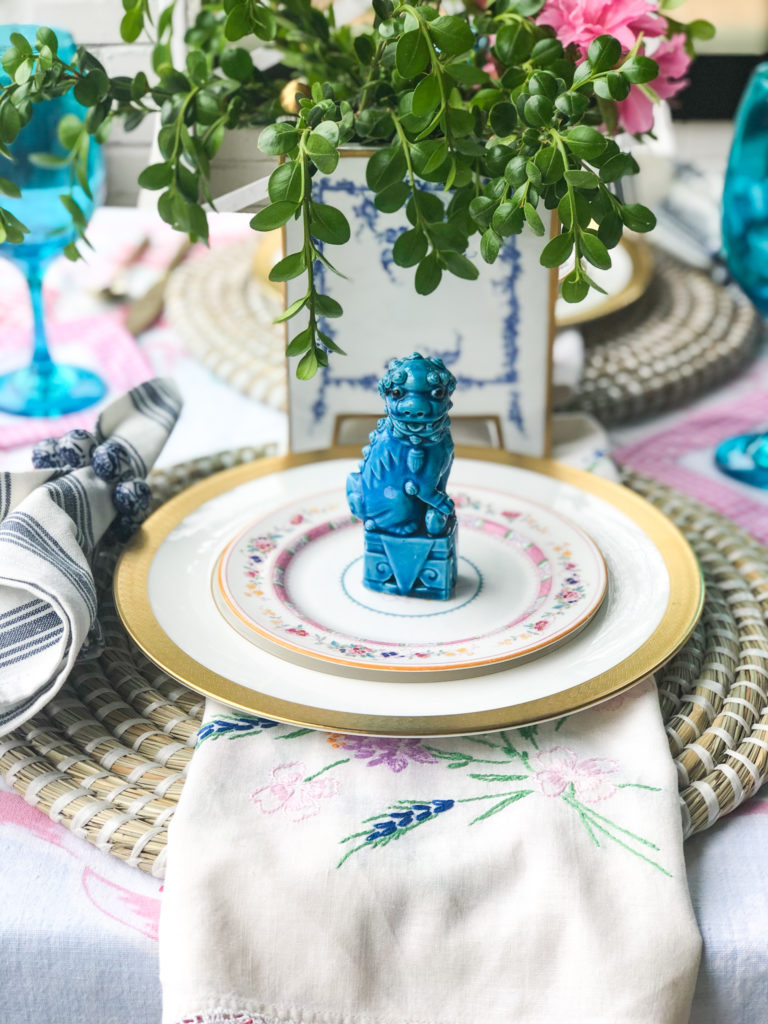 outdoor table set with china and a turquoise foo dog on top of plates
