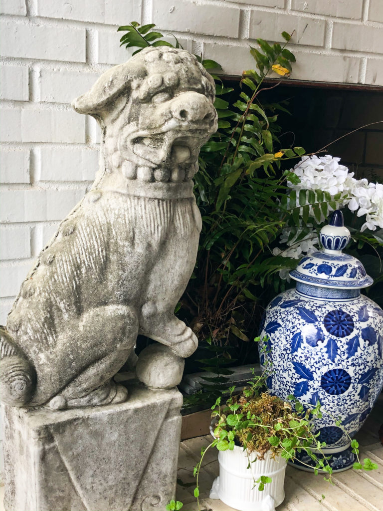 concrete foo dog statue at fireplace with blue chinoiserie jar