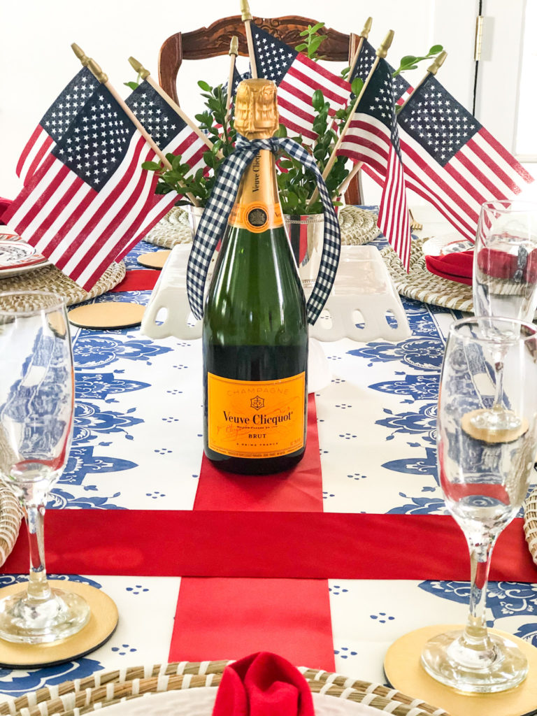table setting with red ribbon cross mini american flags and champagne