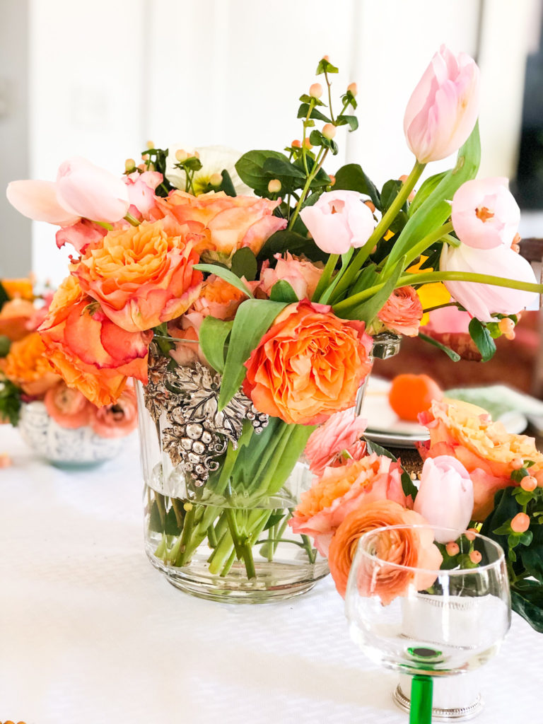 clear ice bucket filled with orange flowers as centerpiece on table