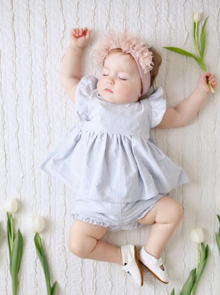 sleeping baby girl in dress and bloomers with headband and tulips