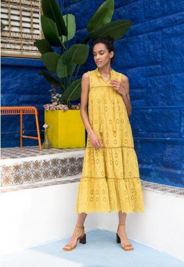 lady wearing mustard yellow eyelet dress on patio with blue wall