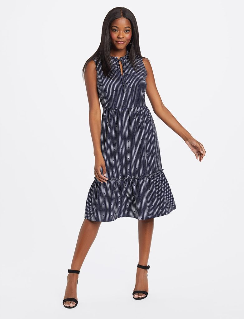 black female wearing navy tiered dress with white heart dots