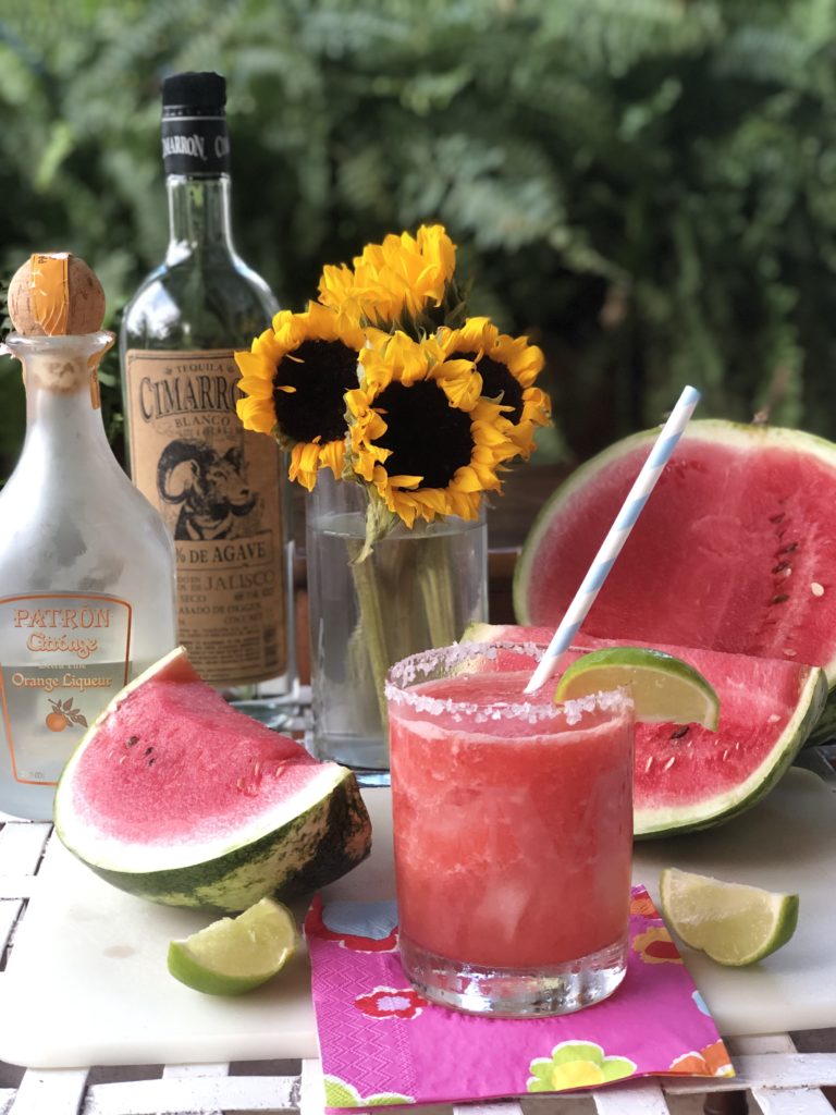 watermelon margarita in glass with lime garnish and sunflowers