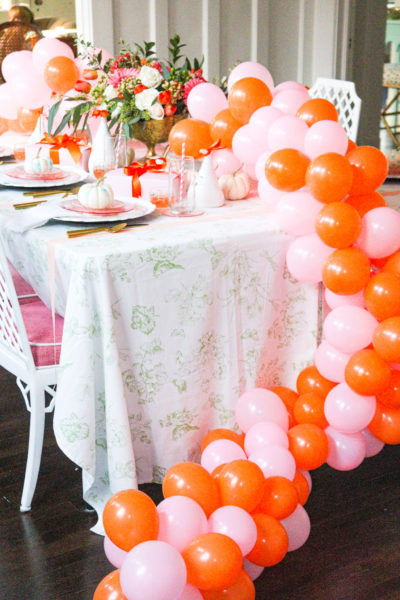 halloween table setting with pink and orange balloon garland centerpiece trailing from table