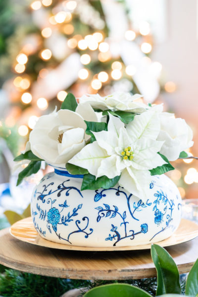 cake made to look like a blue and white chinoiserie vase with white sugar magnolia and poinsettia blooms