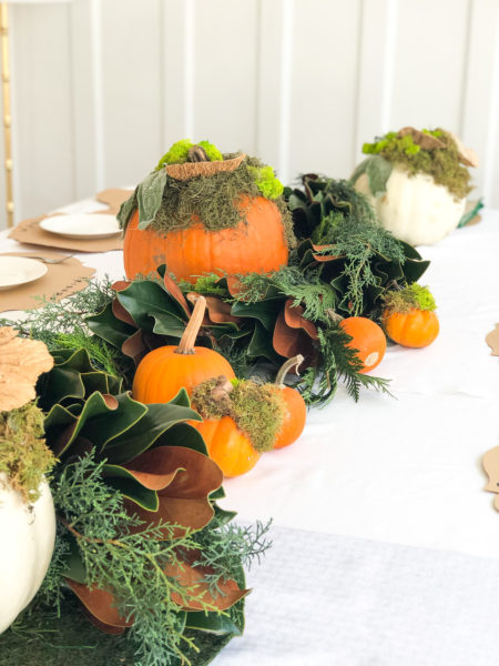 thanksgiving table runner made of live greenery garland and pumpkins
