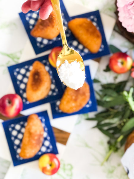 powdered sugar being sprinkled on fried apple hand pies