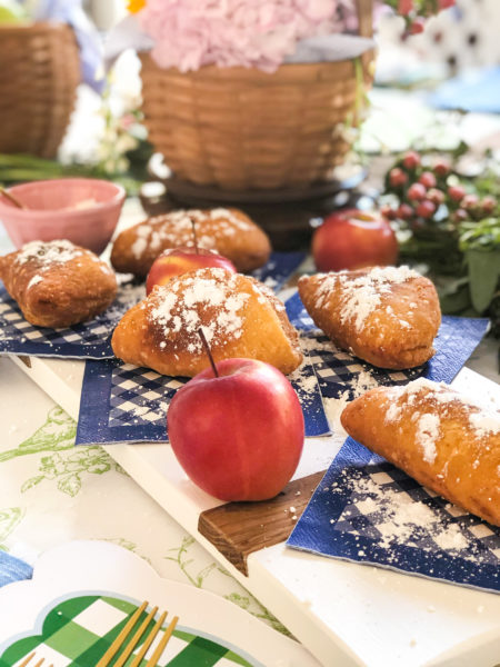 individual fried apple pies sprinkled with sugar on blue and white gingaham paper napkins