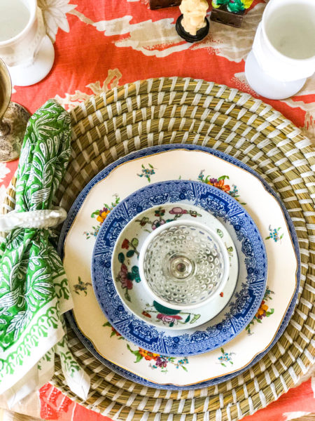 overhead shot of place setting with mixed china patterns on seagrass charger