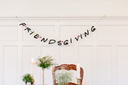 friendsgiving banner on white wall with table set in front of it