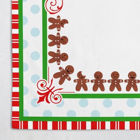 close up view of corner detail on tablecloth with gingerbread men with green and red stropes and blue polka dots
