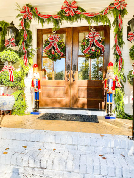 front double door entrance decorated for christmas with wreaths and garlands with plaid bows