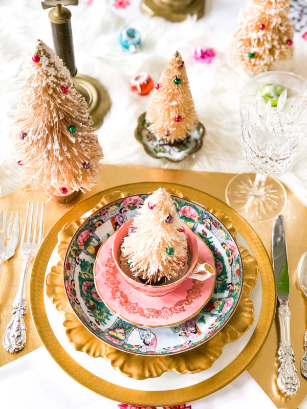 pink and gold christmas table setting with bottle brush trees and colorful ornaments