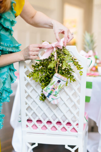 white lattice back chair with greenery and small stocking and lady tying pink bow