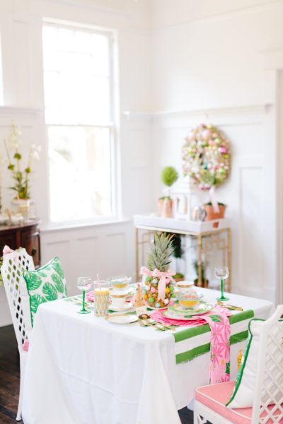 table set for 2 with pink and green christmas brunch items and wreath and bar cart