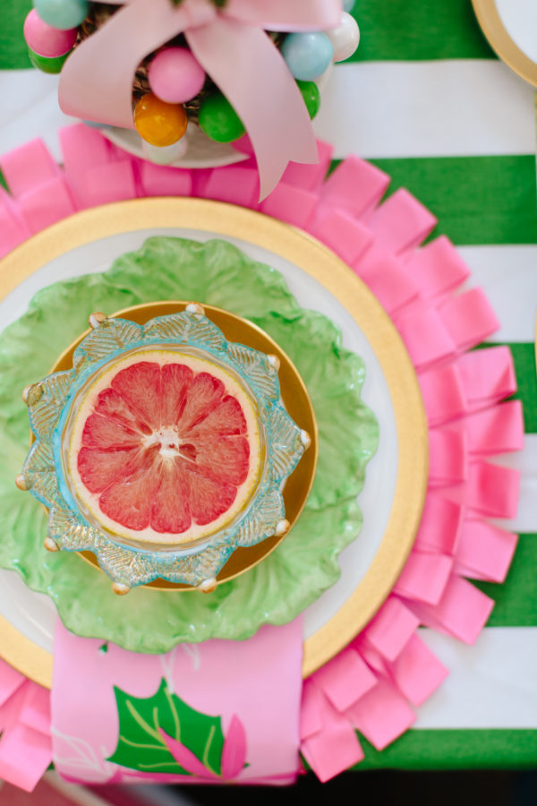 pink and green place setting with half of a grapefruit