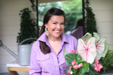 brunette lady in lavender collared shirt holding plants