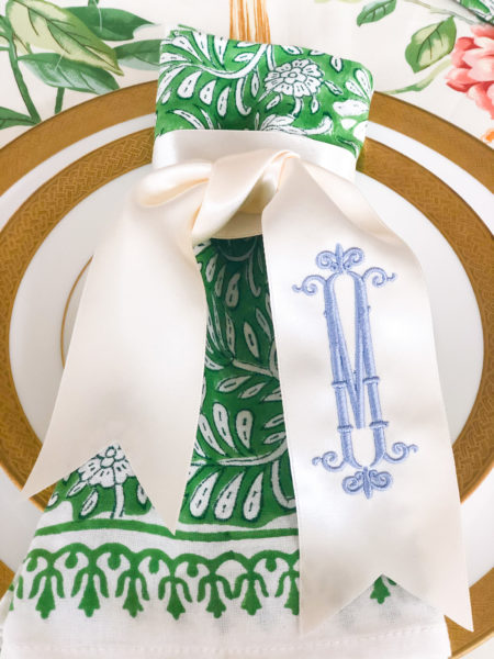 monogrammed ribbon on green napkin and gold and white plates