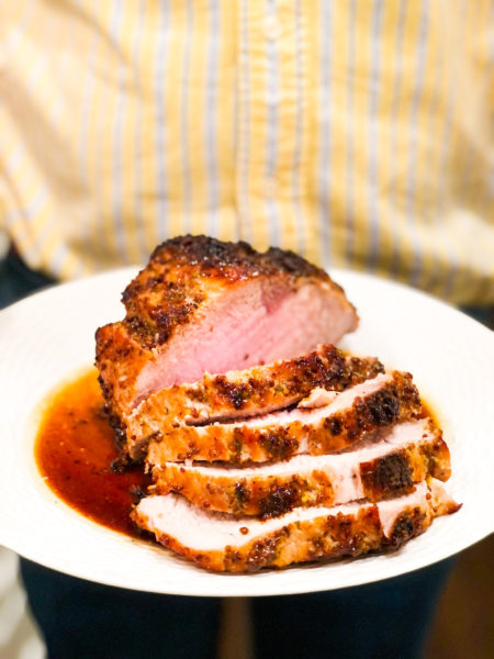 mustard brown sugar thyme pork loin on white plate being held