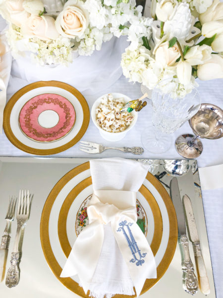 winter white table setting with gold rim plates monogrammed ribbon and flowers