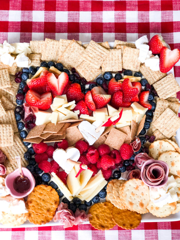 heart shaped charcuterie board on gingham tablecloth