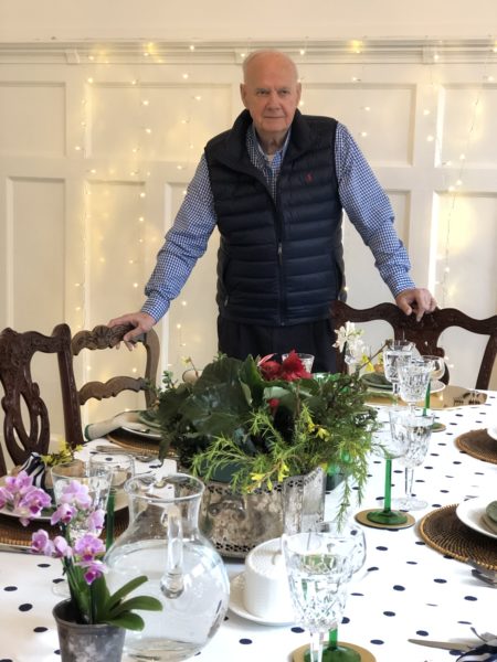 grandfather standing at table for birthday with lights in background