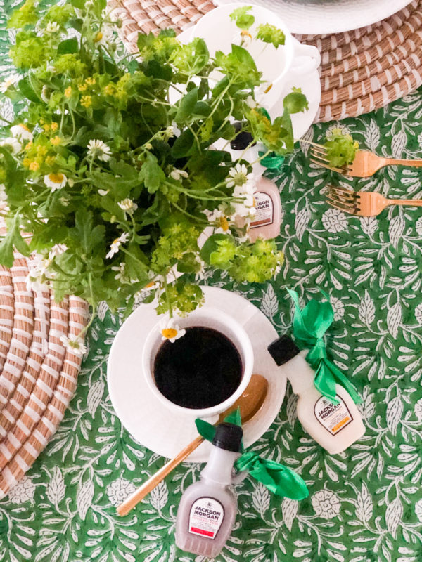 green tablecloth with coffee in white cup and saucer and green plant