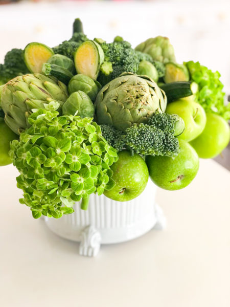 green floral arrangement with green vegetables in white planter complete