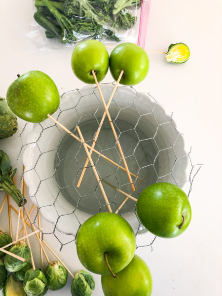 apples being placed in a white planter with chicken wire