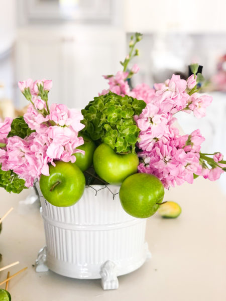 making a floral arrangement with pink and green flowers and apples