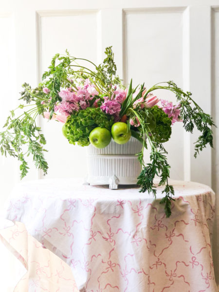 easter flower arrangement on table with white tablecloth and pink bows