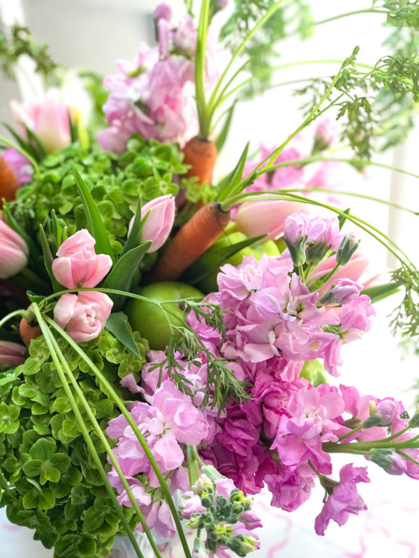 easter flower arrangement in pink and green with orange carrots with stems