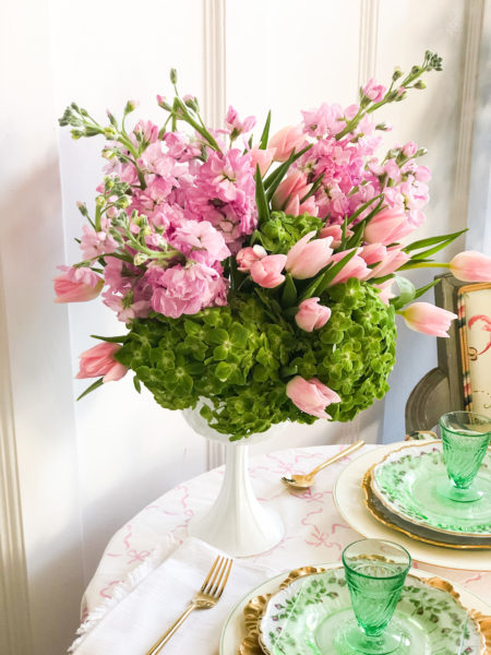 pink and green flowers in a white pedestal vase